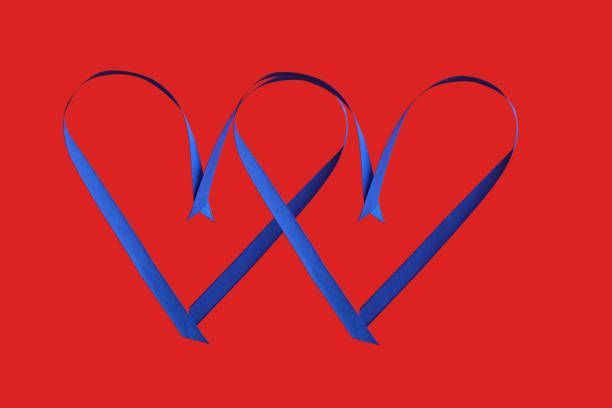 Two linked hearts made of blue satin on red background, top view with space for text. Valentine's day celebration.