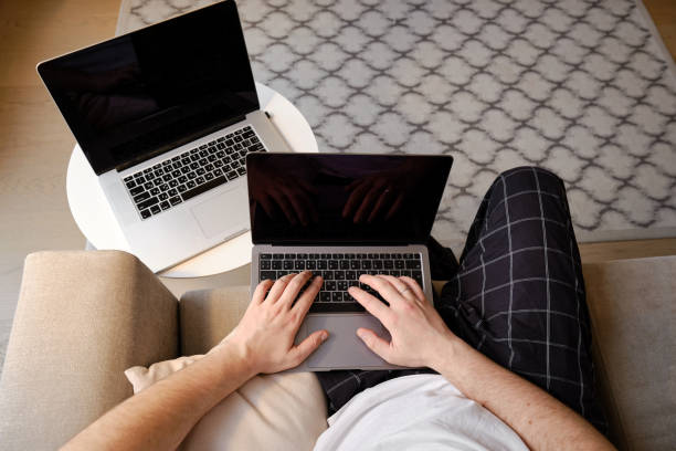 istock A man works on two laptops in the office or at home. Remote work. Home office. A man is typing on a laptop, distance learning for students, surfing the Internet. Business concept 1367375261