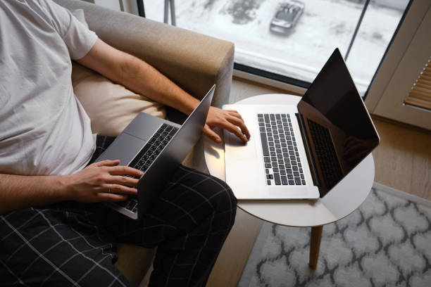 istock A man works on two laptops in the office or at home. Remote work. Home office. A man is typing on a laptop, distance learning for students, surfing the Internet. Business concept 1367375263