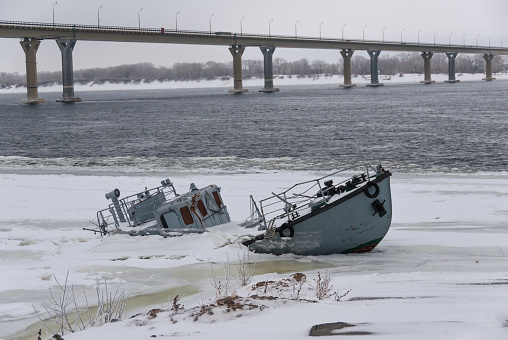 Sinking ship in a frozen river covered with ice