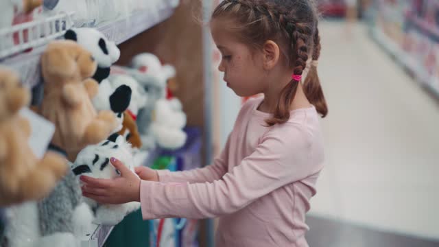 Little Child asks his mother to buy white tiger soft toy in children's department store. Caucasian female children choose fluffy animal toy on supermarket