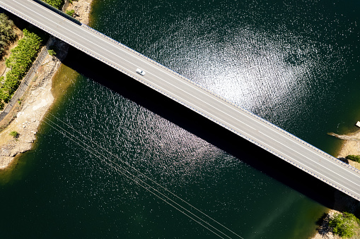 Bridge across reservoir, aerial shot, sunny day green water dam of Avila. Spain