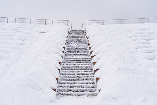 Winter landscape. The concrete staircase of the public space amphitheater goes up. The benches for spectators are covered with a thick layer of snow. Background.