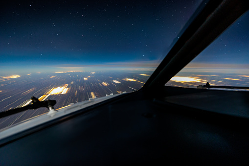 Picture of the windshield and nose of a Boeing 737 flying at night above Kansas. The long exposure blurs the lights on the ground but the stars are sharp because of the limited relative motion