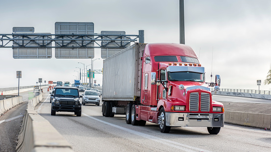 Red truck makes its way through heavy traffic with a container of goods.