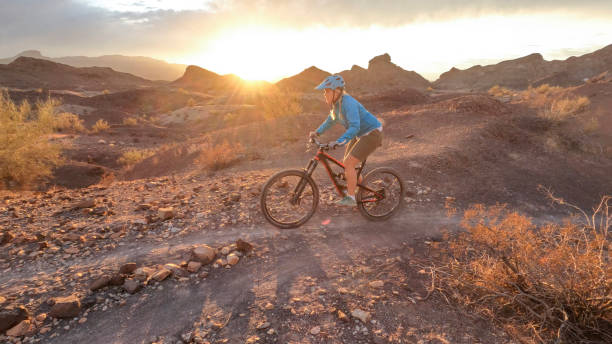 istock Female mountain biker follows desert pathway at sunrise 1367386445