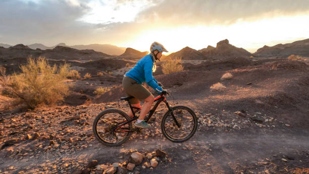 kobieta rowerzysta górski podąża szlakiem pustynnym o wschodzie słońca - 5428 zdjęcia i obrazy z banku zdjęć