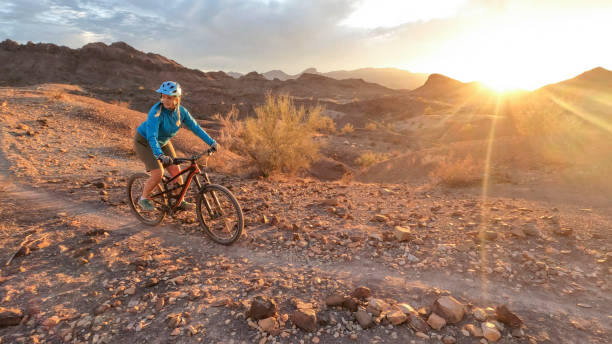 istock Female mountain biker follows desert pathway at sunrise 1367386557