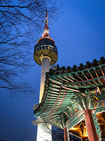 Low angle view of Korean temple in front of N Seoul Tower at Namsan Mountain Park against blue sky