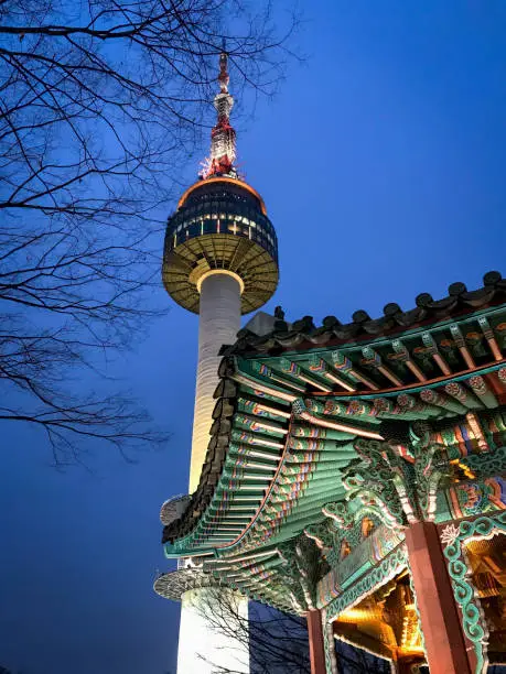 Low angle view of Korean temple in front of N Seoul Tower at Namsan Mountain Park against blue sky