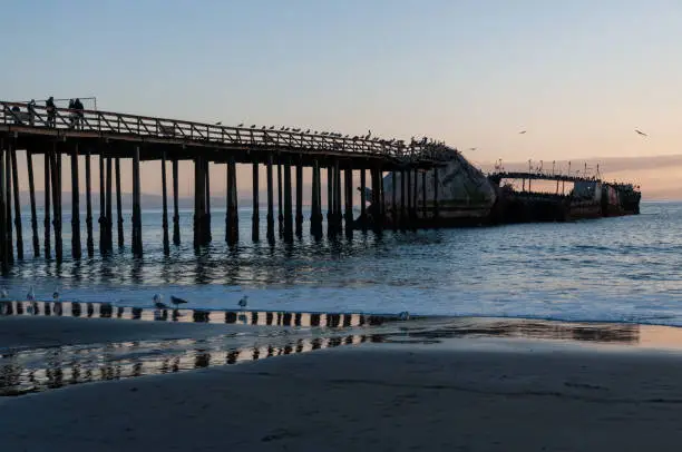 A beautiful sunset over the beach near Aptos, California, highlighting the old derelict pier and an old shipwreck.