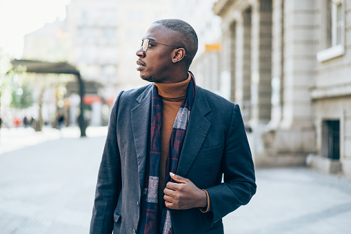 Shot of young confident afro-american man standing outdoor in the city and looking away.