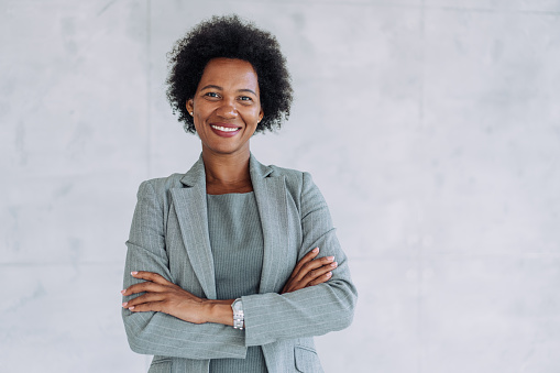 Portrait of beautiful confident smiling african-american businesswoman standing with arms crossed in the office and looking at camera.