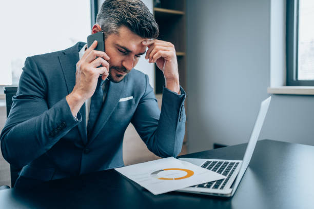 istock Exhausted businessman talking on his mobile phone in office. 1367391537