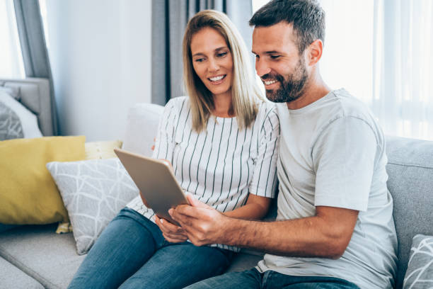 istock Smiling young couple using digital tablet at home. 1367394244