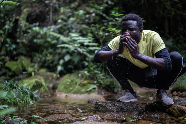 istock Young man drinking water in the forest 1367397271