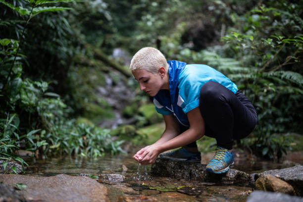 istock Young woman drinking water in the forest 1367398648