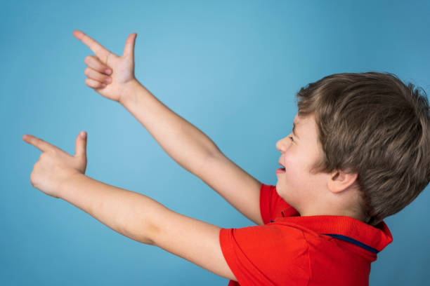 boy cheerfully shoots his fingers folded into the shape of a pistol. the boy put his fingers in the shape of a gun stock photo