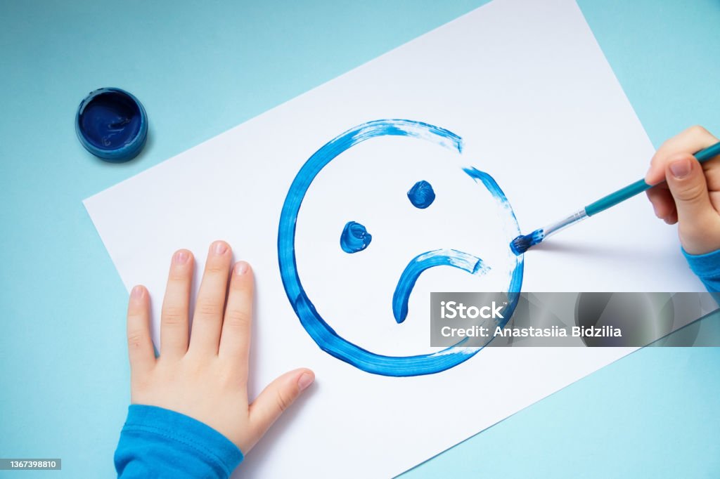 Top view of the child hands,drawing sad face.Blue monday and mental health concept. Blues Music Stock Photo