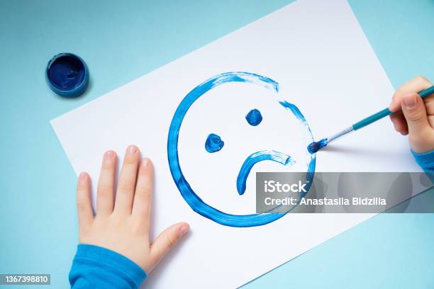 Top View Of The Child Handsdrawing Sad Faceblue Monday And Mental Health Concept Stock Photo - Download Image Now