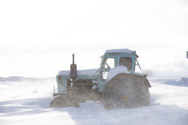 istock Tractor on a snow-covered field against a cloudy sky. 1367399774