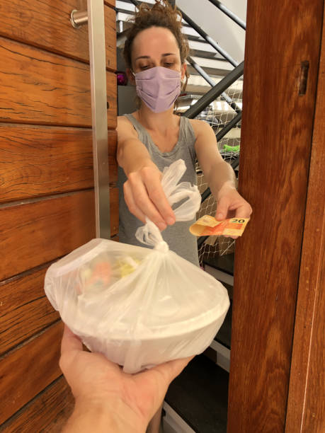 femme en masque de protection recevant un livreur de nourriture. - real people customer caucasian technology photos et images de collection