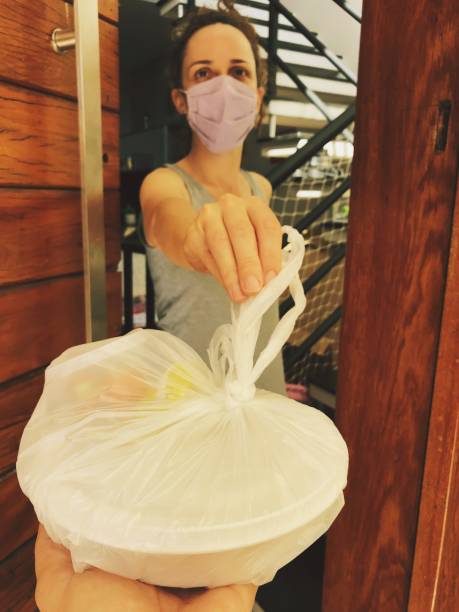 femme portant un masque de protection recevant un livreur de nourriture. - real people customer caucasian technology photos et images de collection