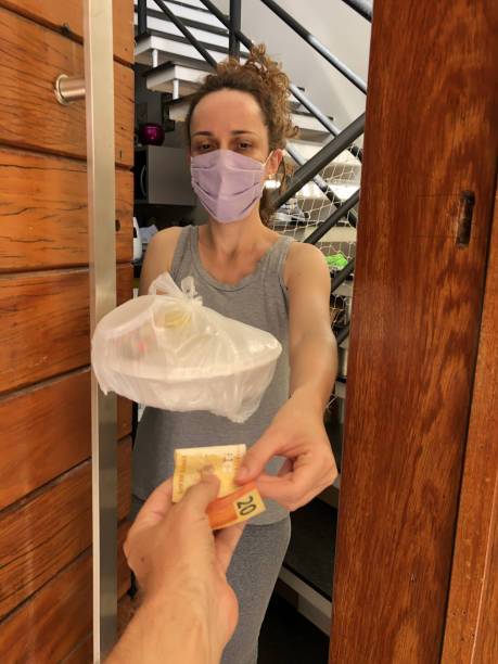 femme portant un masque de protection recevant un livreur de nourriture. - real people customer caucasian technology photos et images de collection