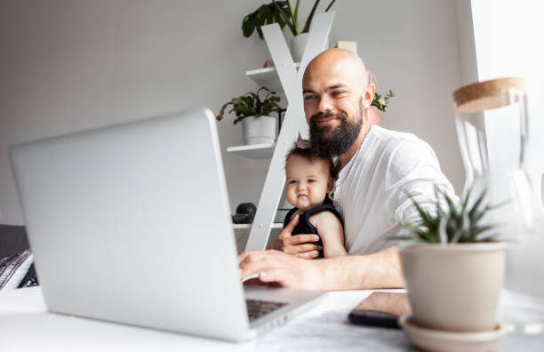 istock Happy bearded working father with little daughter uses laptop while sitting at table in modern room 1367401042