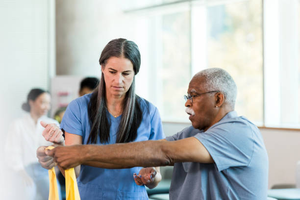 istock Physical therapist guides senior man using elastic band 1367401278
