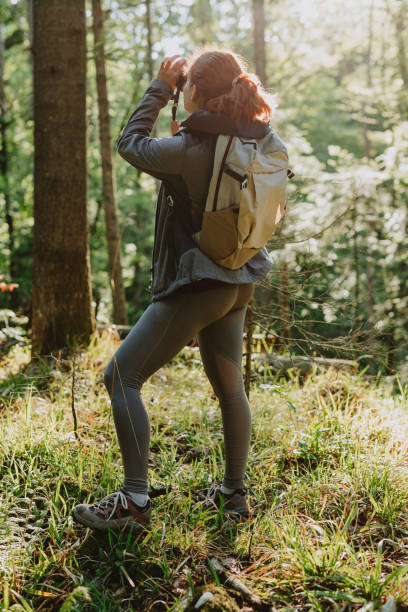 istock An Anonymous Female Standing Somewhere In The Forest And Looking At The Trees With Her Binoculars 1367402633