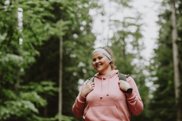 una bella femmina sorridente durante un'escursione nella foresta - sovrappeso foto e immagini stock