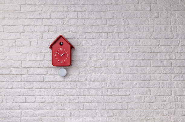istock Red cuckoo bird clock with pendulum on white brick wall background with copy space 1367404152