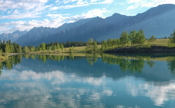 istock View across calm lake to meadow and mountain range 1367406021