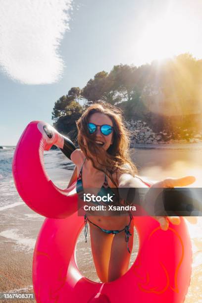 Smiling Young Woman With Inflatable Flamingo At The Beach Stock Photo - Download Image Now