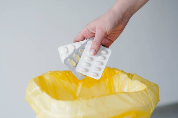 istock Woman's hand throws expired blister pills to the trash bin. 1367411611