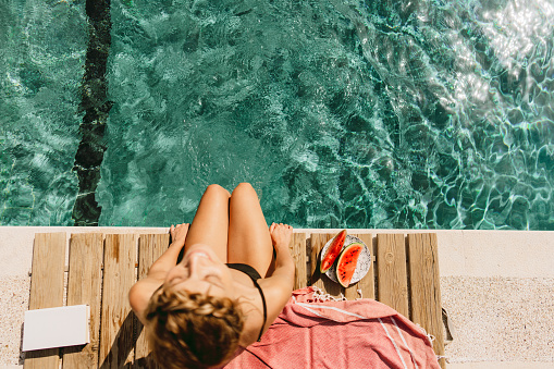 Photo of a young woman enjoying a sunny day by the pool