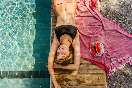 Photo of a young woman enjoying a sunny day by the pool