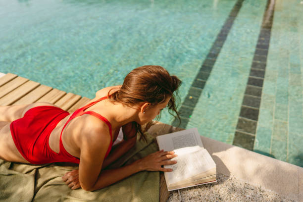 Reading a book by the pool stock photo
