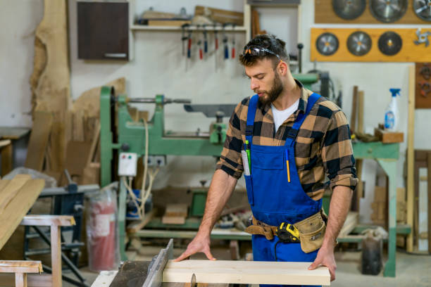 istock Handsome carpenter preparing, measures and cutting boards on cutting machine 1367420362