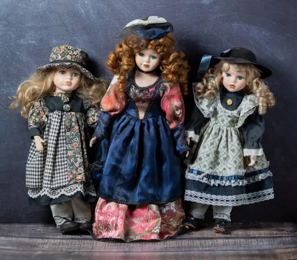 Photo of Old vintage porcelain dolls on dark background. Concept of time. Stock photo. Elegant dresses.