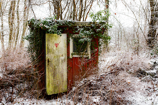An old worn and torn toilet house in winter forest,