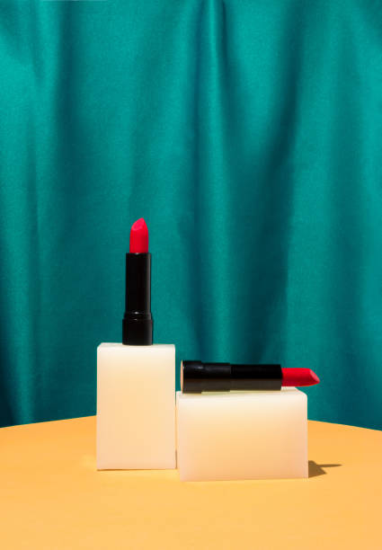 istock Minimal retro style scene with red lipstick on bright sandy table and vintage silk green curtain. Creative beauty product display. Valentines day gift. 1367429573