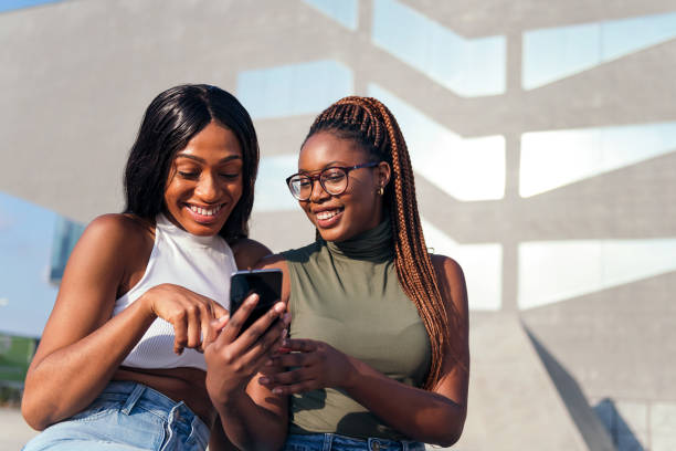 istock two young friends having fun looking the phone 1367430633
