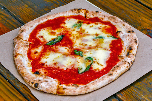 Pizza Margherita on rustic wooden table. Created in Naples, today it is one of the culinary specialties of the city of Sao Paulo, Brazil