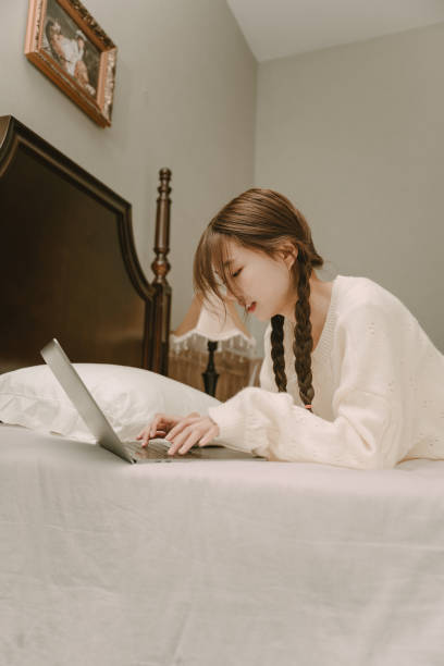 istock Young Asian women playing computer in bed 1367435210