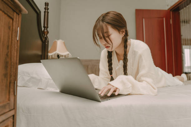 istock Young Asian women playing computer in bed 1367435216