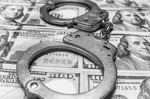 A pair of worn handcuffs with hundred dollar bills as a concept for bail, criminal justice reform, police budgets, the costs of crime or many others
