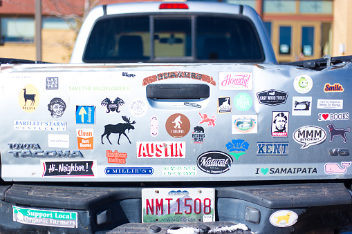 Santa Fe, NM: Bumper stickers on a pickup truck with a New Mexican license plate; stickers include “Austin” and “Smile” and “Disobey.”