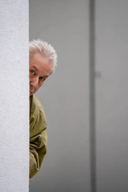 Businessman playing peekaboo showing head from behind the building